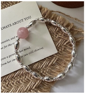 Macro detail of S925 silver beaded bracelet featuring a smooth pink crystal center stone