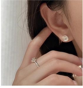 Detail view of matte silver earrings with textured finish and zircon ring on a model