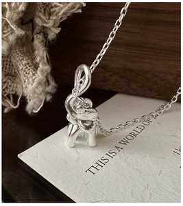 Macro close-up of S925 sterling silver elephant pendant necklace on a decorative card