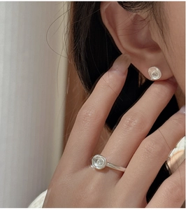 Detail of minimalist S925 silver ring and earrings set with irregular concave design