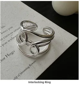 Close-up of a silver criss-cross ring with an adjustable open design on paper