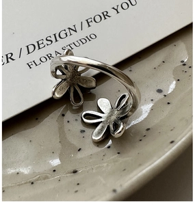 Macro shot of silver vintage flower ring with adjustable open band on ceramic tray