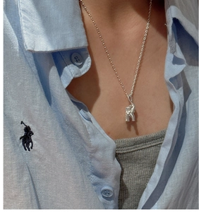 Detail of S925 sterling silver elephant pendant on a delicate chain worn over a blue shirt