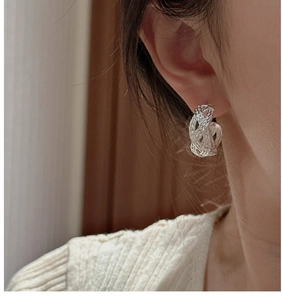 Close-up of S925 sterling silver woven earrings worn by a model in warm lighting