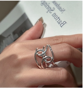 Detail of multi-layered geometric hollow intertwined silver ring on woman's finger
