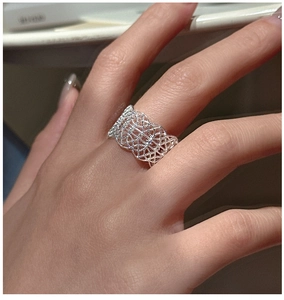Detailed view of an intricate silver hollow lace mesh ring on a finger