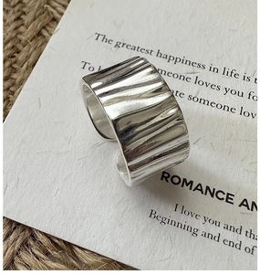 Macro shot of silver wide ring featuring organic wrinkled texture on jute backdrop