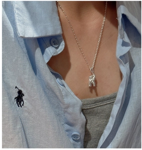 Detail of silver elephant pendant necklace worn on neck showing vintage artistic design
