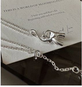 Macro detail of a 925 sterling silver elephant pendant on a minimalist chain necklace