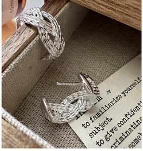 Macro shot of S925 sterling silver woven earrings showing intricate metal twist details
