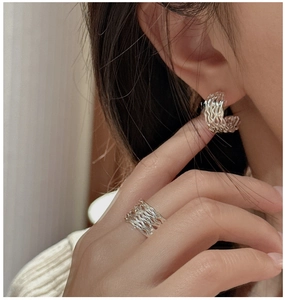 Detailansicht silberner dreilagiger Ohrringe und Ring am Modell für eleganten Look