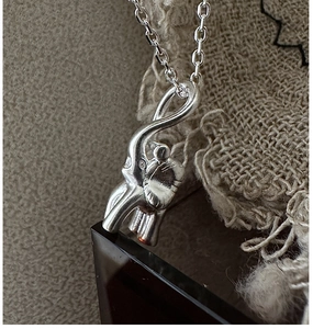 Macro shot of 925 sterling silver elephant pendant with detailed texture on linen