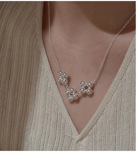 Gros plan du collier à pendentif fleur en argent sterling S925 sur le cou du modèle