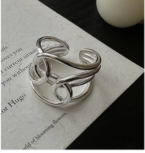 Macro detail of multi-layer interwoven silver ring on minimalist vintage paper