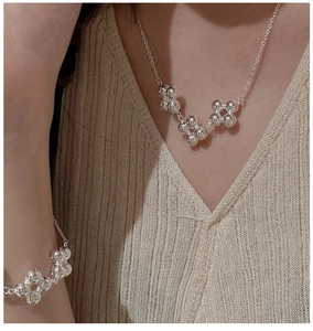 Gros plan sur un ensemble collier et bracelet trèfle en argent S925 porté par un mannequin