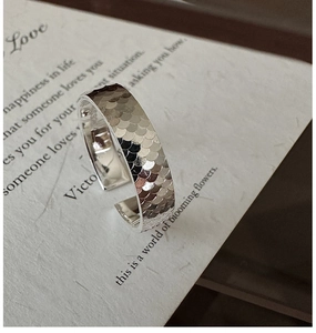 Détail macro d'une bague réglable argentée avec motif d'écailles sur papier vintage