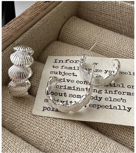 Macro detail of S925 sterling silver shell earrings displayed in a rustic wooden jewelry box