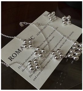 Detail of S925 sterling silver ball flower necklace and earrings set on white display board