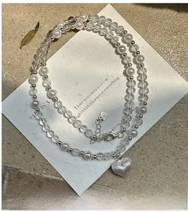 Détail macro du collier de perles avec pendentif cœur givré et cristaux blancs