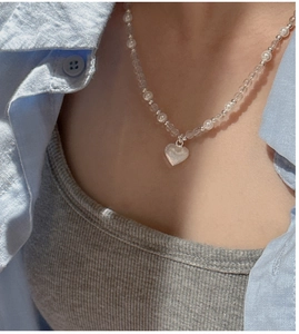 Détail du collier de perles avec pendentif cœur et cristaux blancs sur un mannequin