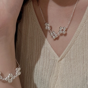 Ensemble collier et bracelet trèfle en perles d'argent S925 porté sur un col en V