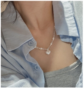 Gros plan d'un collier en perles d'argent S925 avec un pendentif coeur mat porté