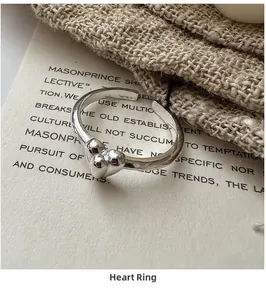 Close-up of S925 sterling silver heart ring with polished mirror finish on knit background