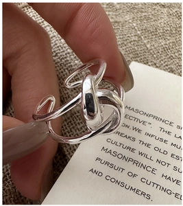 Detailed close-up of a silver knot ring featuring abstract layered geometric design