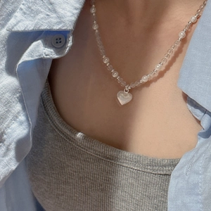 Collier en argent S925 avec perles et pendentif cœur porté sur une chemise bleue