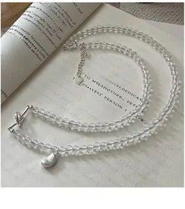 Dettaglio macro del ciondolo in argento e perle trasparenti su sfondo libro vintage