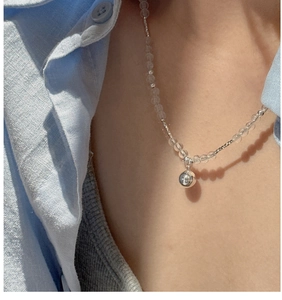 Detail view of a beaded silver necklace with clear crystals and a polished round pendant