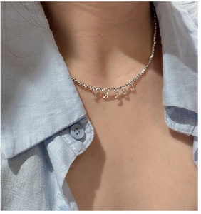 Détail du collier à perles en argent S925 avec pendentif LUCKY sur le cou du mannequin