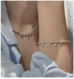 Détail de parure collier et bracelet à billes argentées avec pendentif LUCKY