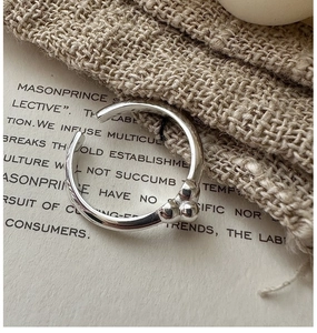 Detailed close-up of a minimalist S925 silver open ring with three polished metal spheres