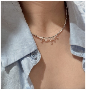 Détail du collier de perles en argent S925 avec pendentifs LUCKY porté par un mannequin