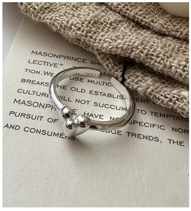 Close-up of S925 sterling silver open ring with three heart charms on woven fabric