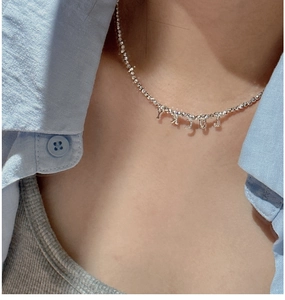 Gros plan du collier en perles d'argent S925 avec pendentif lettre LUCKY élégant