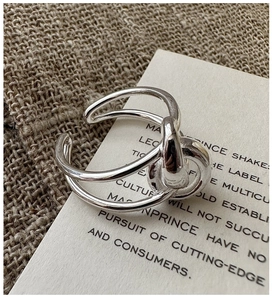 Macro shot of interlaced silver-colored open ring on minimalist textured linen