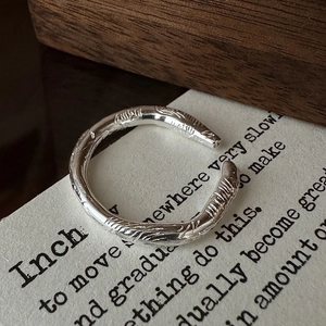 Minimalist S925 sterling silver ring with irregular hammered texture on dark wood background
