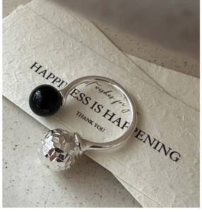Détail d'une bague en argent 925 avec perle d'agate noire et boule métallique facettée
