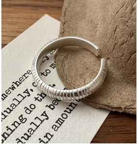 Détail d'une bague en argent S925 avec gaufrage vertical texturé sur une surface en bois