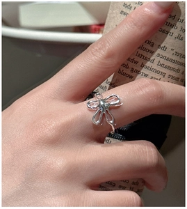 Close-up of S925 sterling silver hollow bow ring with liquid metal texture on finger