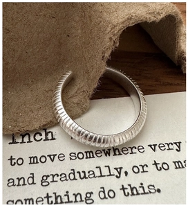 Vue macro d'une bague en argent avec texture mate horizontale et design ouvert