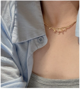 Close-up of golden S925 silver beaded necklace with LUCKY letter charms on a model