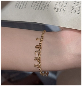 Detail view of gold S925 beaded bracelet featuring LUCKY letter pendants on wrist