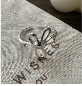 Macro view of adjustable silver flower ring on a textured gift pouch with soft lighting