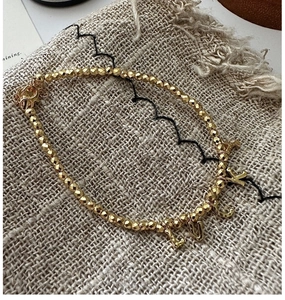 Detailed macro view of gold beaded LUCKY letter charm bracelet with faceted metallic beads