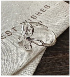 Macro view of abstract streamline S925 sterling silver flower ring on fabric bag