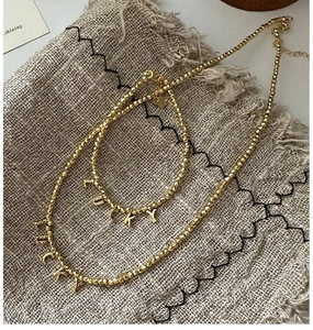 Detailed view of gold beaded necklace and bracelet set with LUCKY letter charms