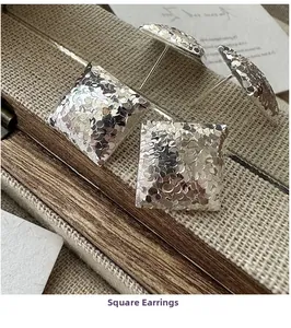 Detailed view of square silver earrings featuring a unique hammered ice texture finish